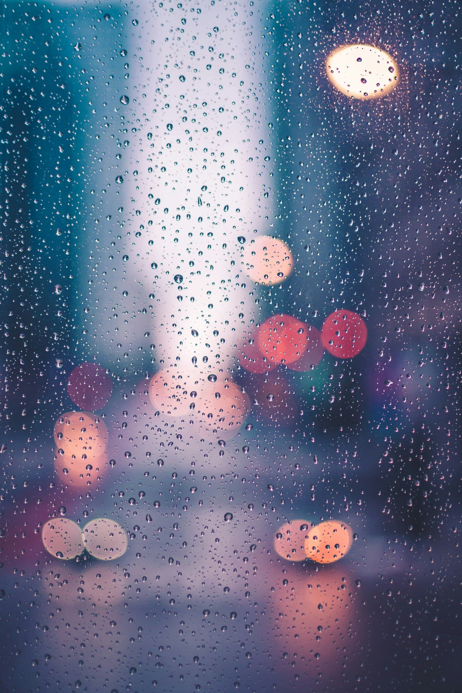 Regentropfen auf einem Fenster bei Dämmerung